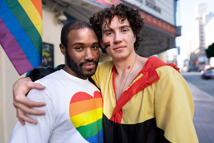 Two friends embracing, one wearing a rainbow heart shirt