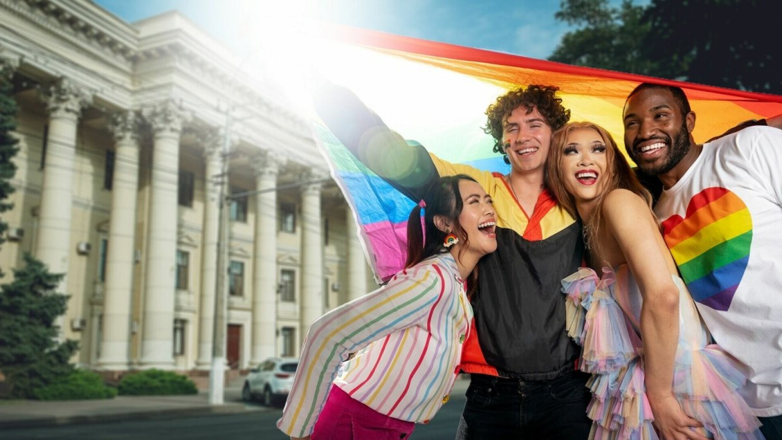 Group of friends celebrating under a rainbow flag